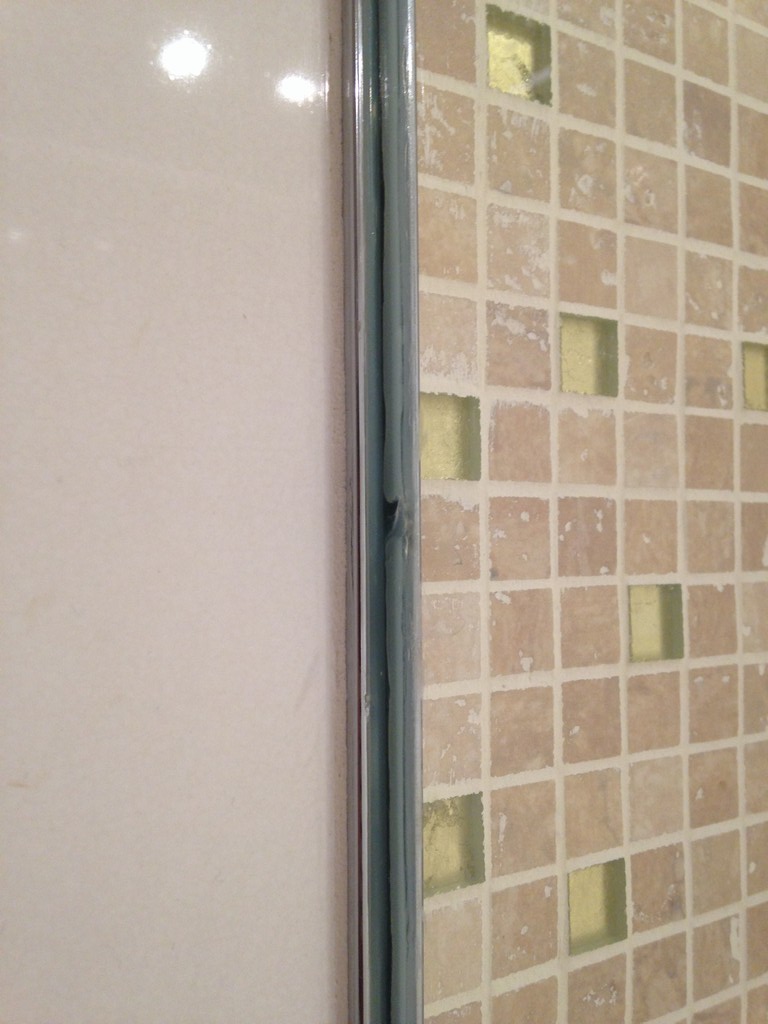 Rail de la paroie de douche dans l'épaisseur du carrelage du mur
